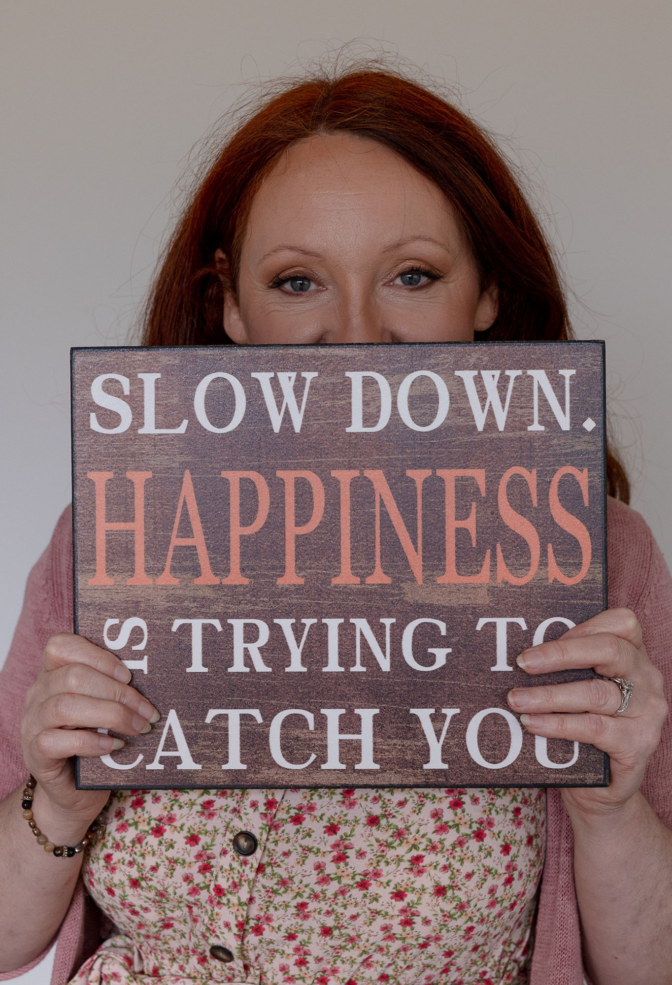 Michelle from Transition Nutrition holding a sign that says “Slow down. Happiness is trying to catch you.”